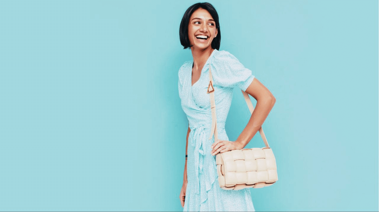 A photo of a woman in a blue dress wearing an off-white sling bag. 
